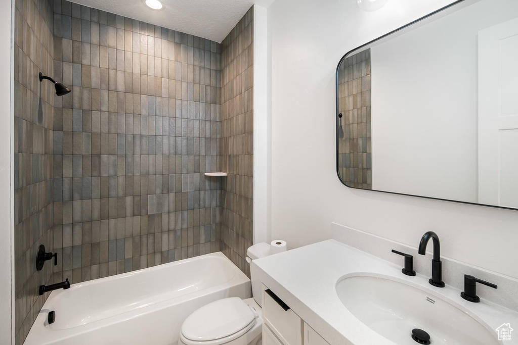 Full bathroom with tiled shower / bath, vanity, and toilet