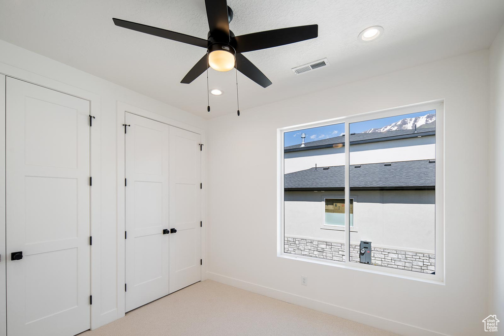 Spare room with a healthy amount of sunlight, ceiling fan, and light colored carpet