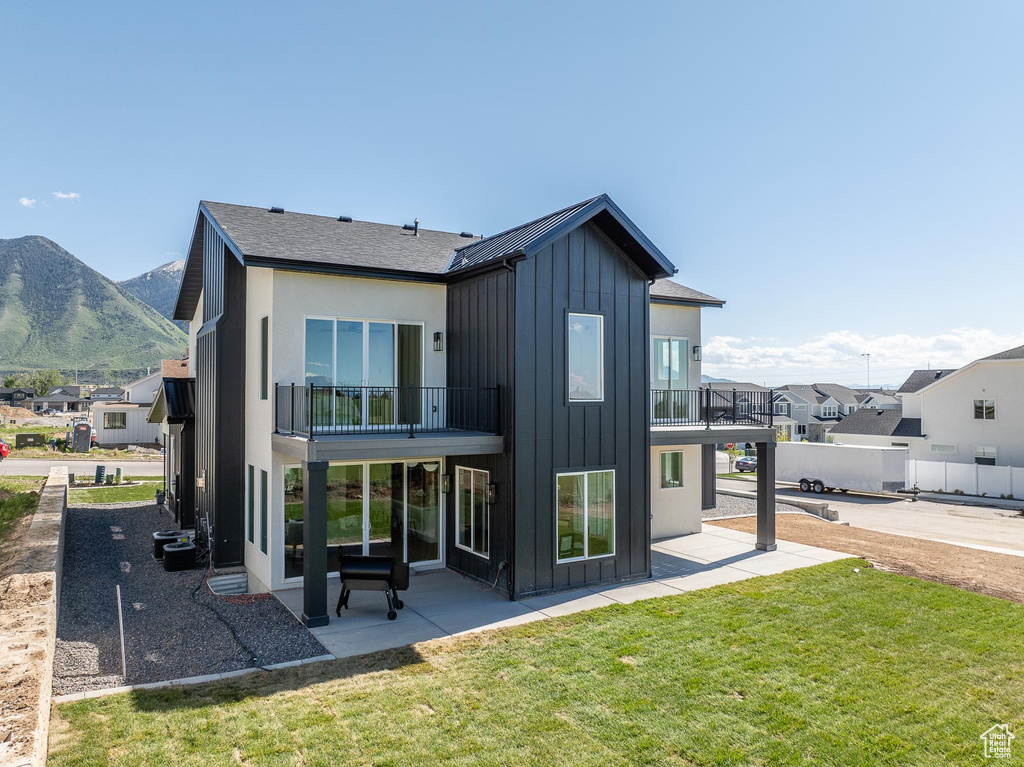 Rear view of house featuring a patio, a balcony, a mountain view, and a yard