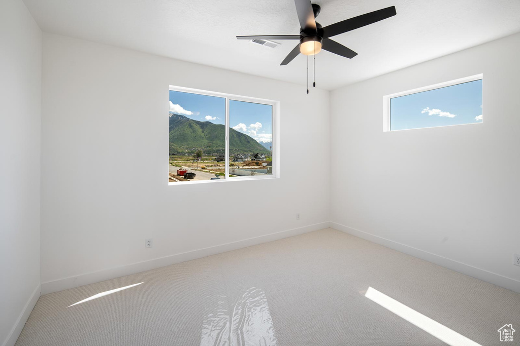 Unfurnished room with ceiling fan, a healthy amount of sunlight, and carpet flooring