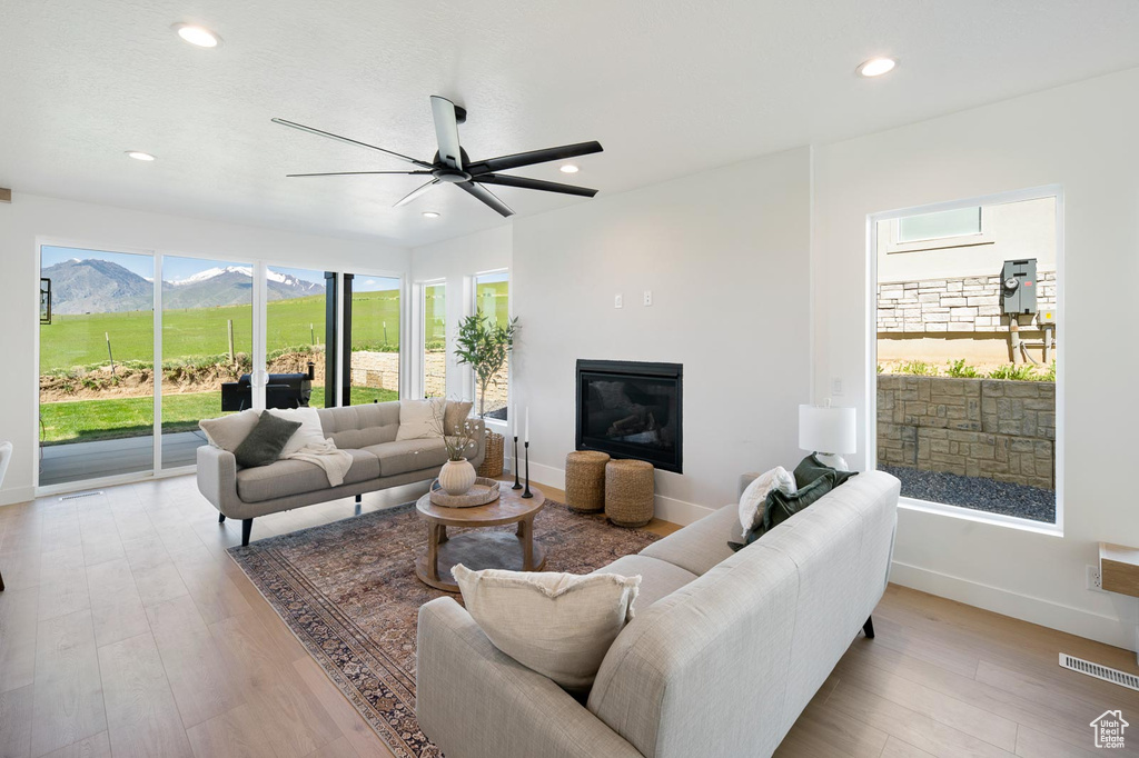 Living room with ceiling fan, a mountain view, and light hardwood / wood-style flooring