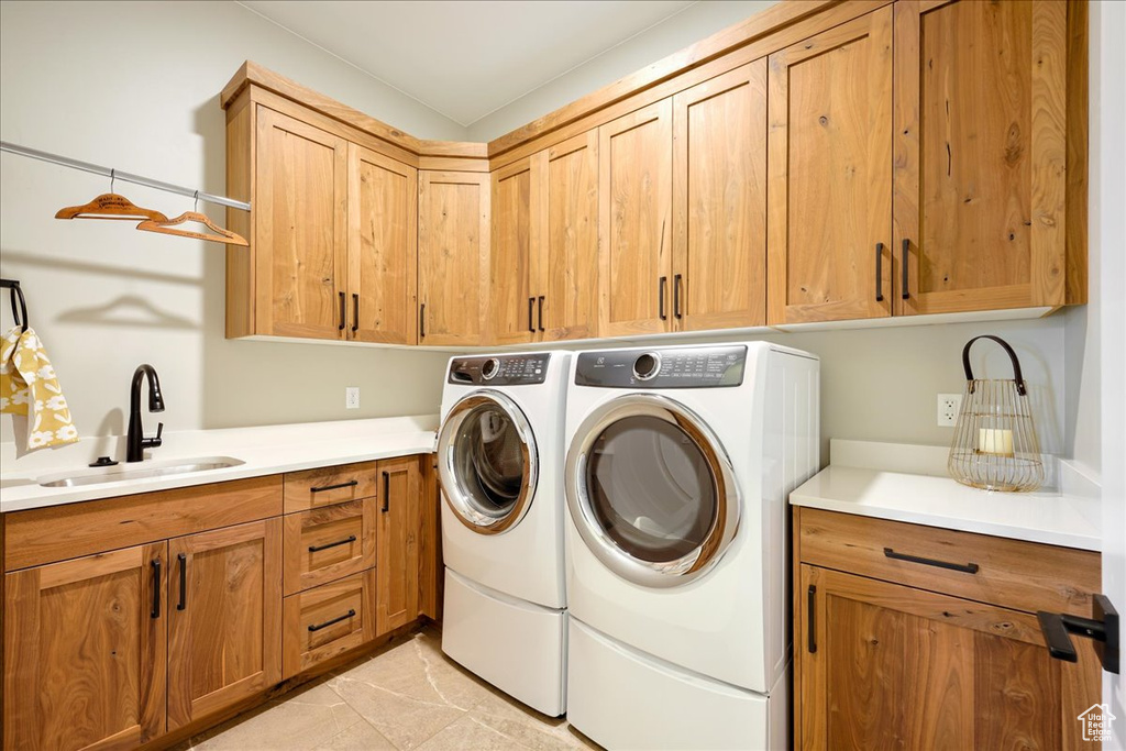 Laundry room with cabinets, sink, light tile flooring, and washer and clothes dryer