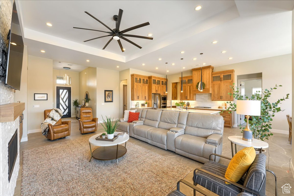 Living room with a raised ceiling, ceiling fan, and sink