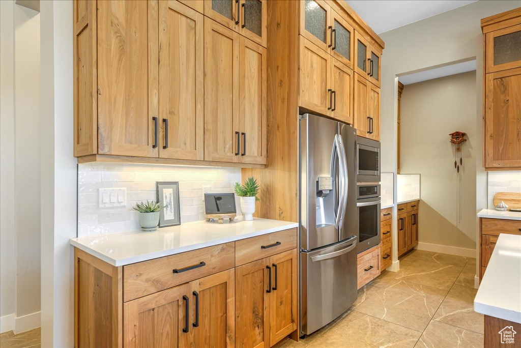 Kitchen featuring appliances with stainless steel finishes, tasteful backsplash, and light tile floors