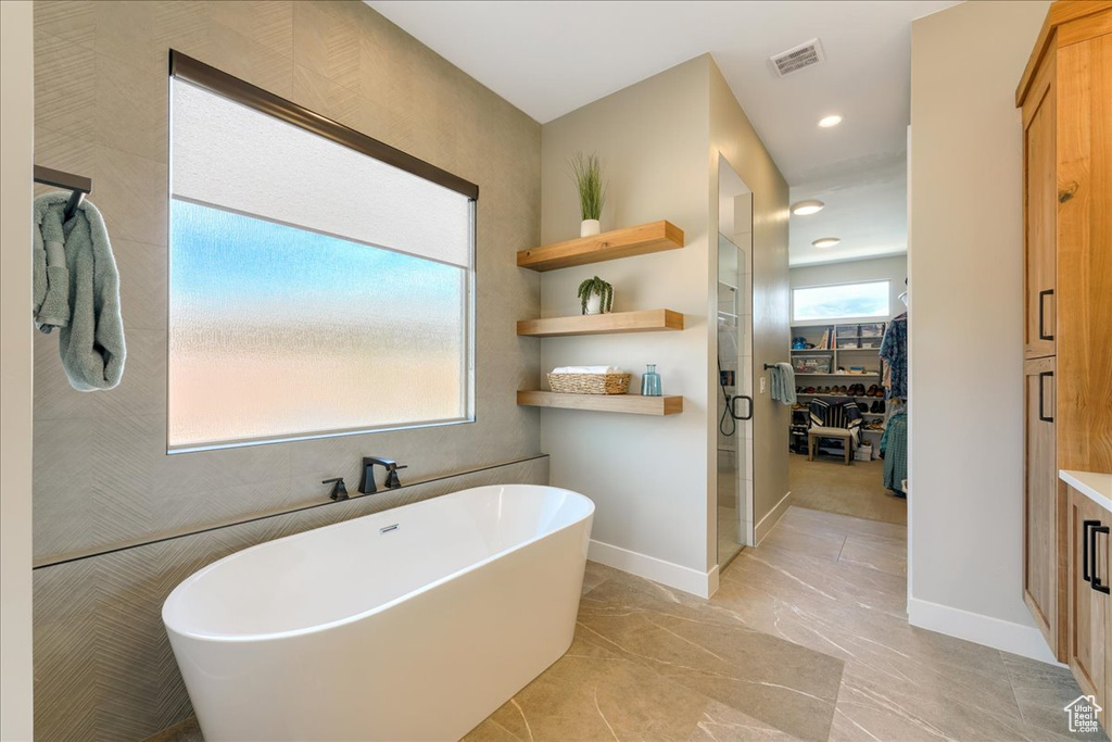 Bathroom with a washtub, tile flooring, and vanity