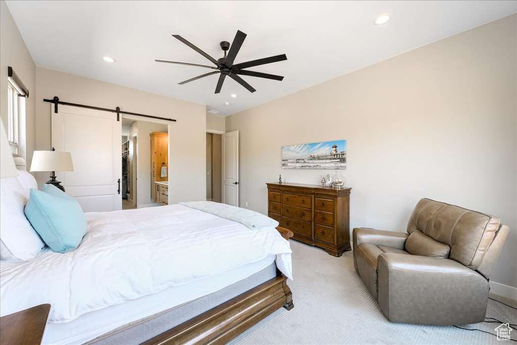 Carpeted bedroom with ensuite bath, a spacious closet, ceiling fan, and a barn door