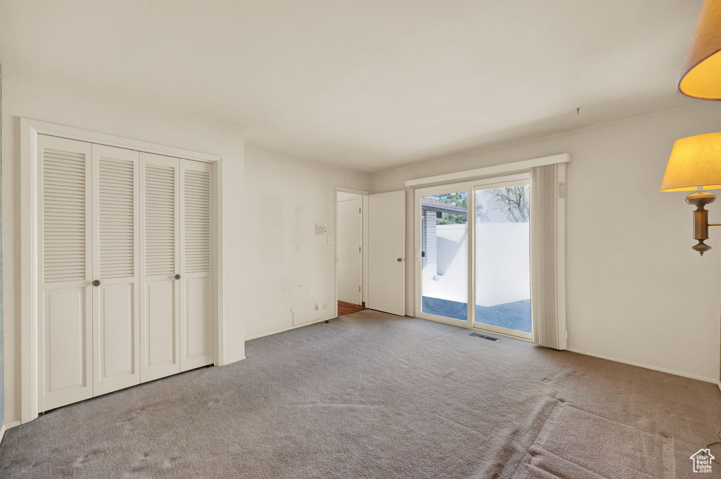 Unfurnished bedroom featuring light carpet, a closet, and access to outside