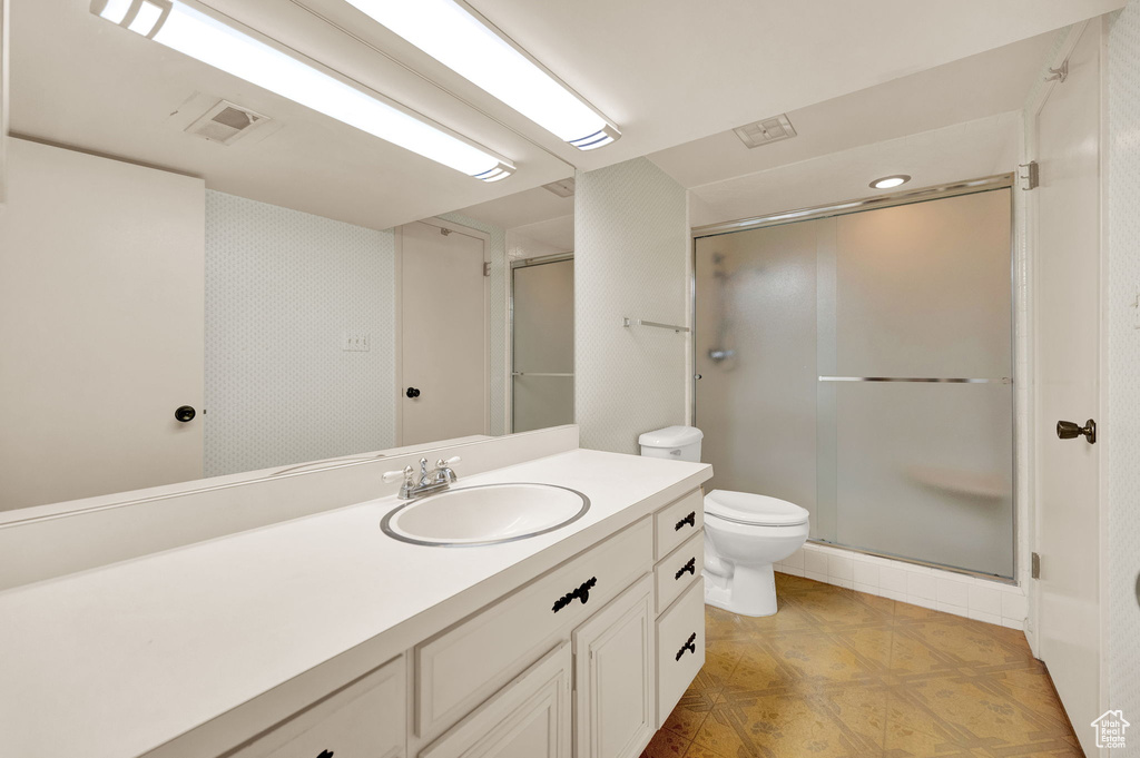 Bathroom with oversized vanity, an enclosed shower, toilet, and tile flooring
