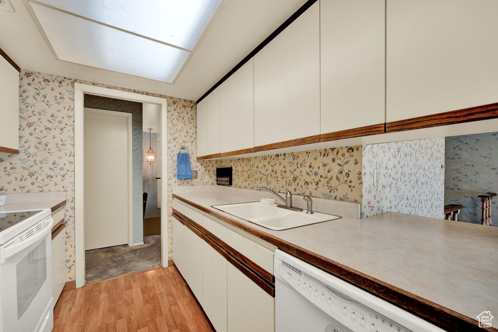 Kitchen featuring light hardwood / wood-style flooring, white cabinets, white appliances, and sink