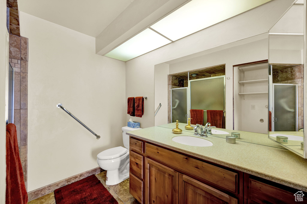 Bathroom with vanity, toilet, tile floors, and a shower with shower door