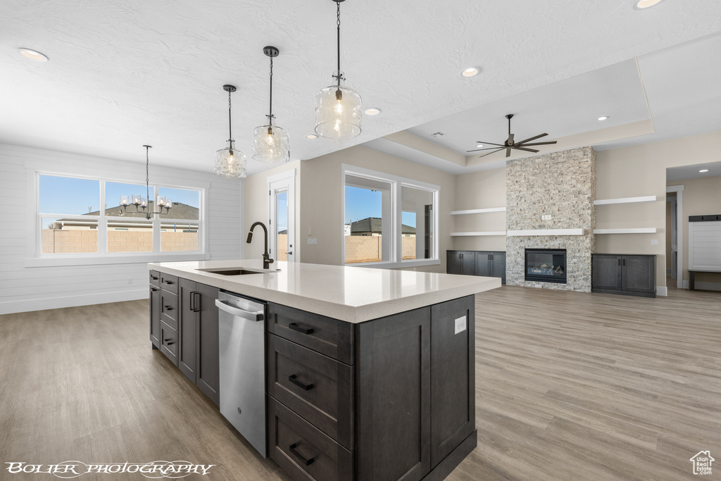 Kitchen with sink, a stone fireplace, light hardwood / wood-style floors, and a raised ceiling
