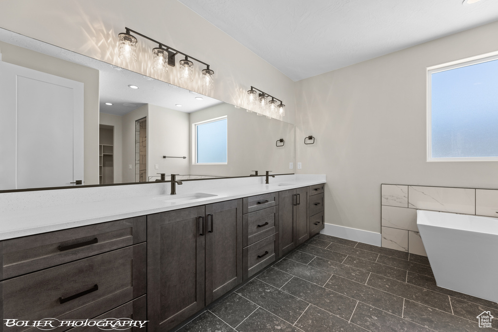 Bathroom with a bathtub, tile floors, a wealth of natural light, and dual bowl vanity