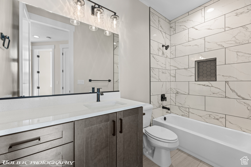 Full bathroom featuring toilet, vanity with extensive cabinet space, and tiled shower / bath