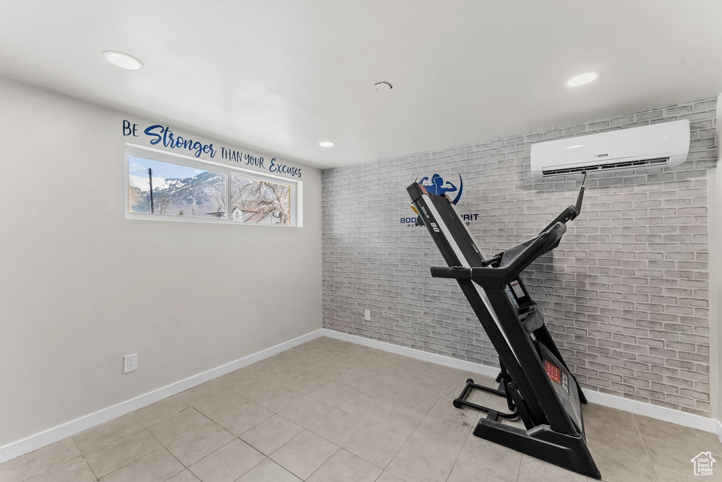Workout area with brick wall, light tile floors, and a wall mounted AC