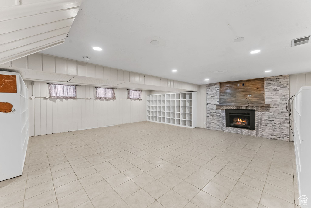 Interior space with wood walls, light tile floors, and a fireplace