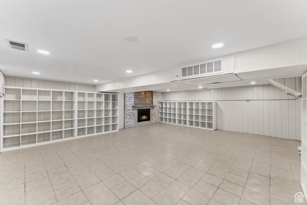 Basement with a large fireplace and light tile flooring