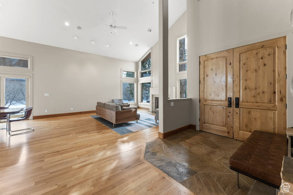 Entrance foyer with high vaulted ceiling, ceiling fan, and light hardwood / wood-style floors