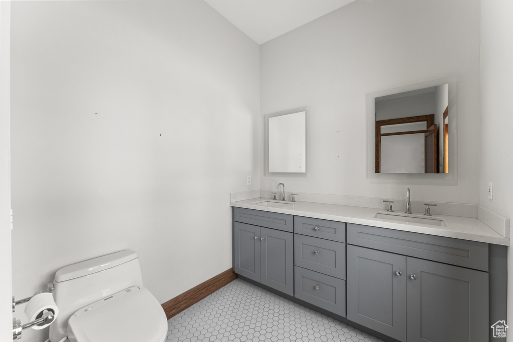 Bathroom featuring toilet, tile floors, and dual vanity
