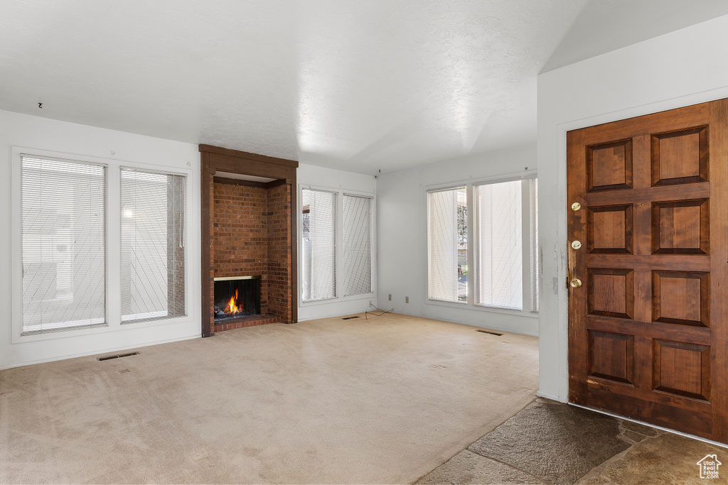 Entryway with brick wall, dark carpet, and a brick fireplace