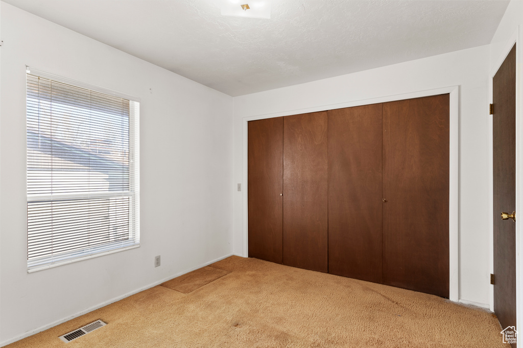 Unfurnished bedroom with light colored carpet and a closet