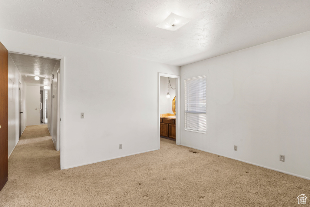 Unfurnished bedroom with light colored carpet and connected bathroom