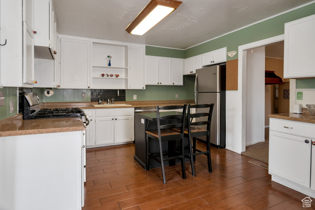 Kitchen with white cabinetry, stainless steel fridge, tasteful backsplash, range, and sink
