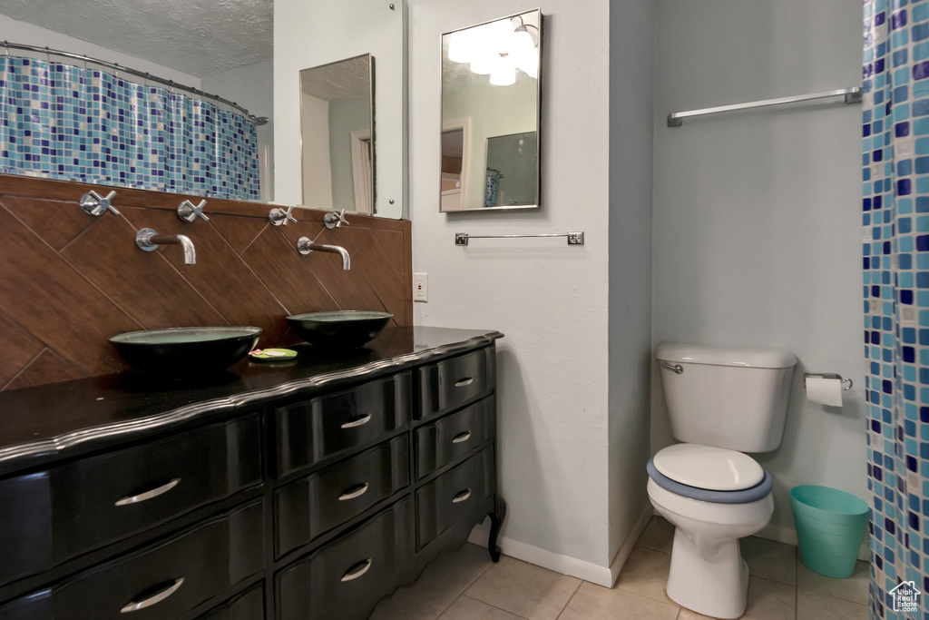 Bathroom with toilet, a textured ceiling, tasteful backsplash, vanity, and tile floors