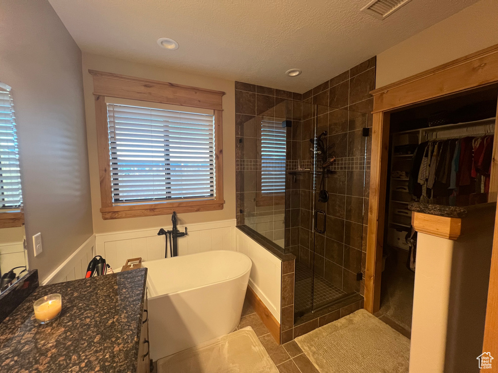 Bathroom featuring tile floors, vanity, a textured ceiling, and plus walk in shower