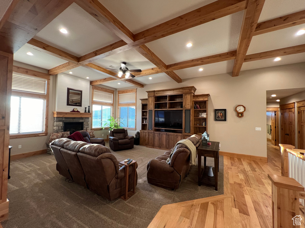 Living room featuring wood-type flooring, beamed ceiling, a fireplace, coffered ceiling, and ceiling fan