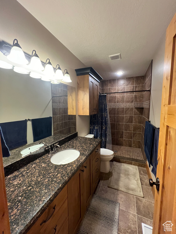 Bathroom with large vanity, toilet, a shower with curtain, a textured ceiling, and tile floors