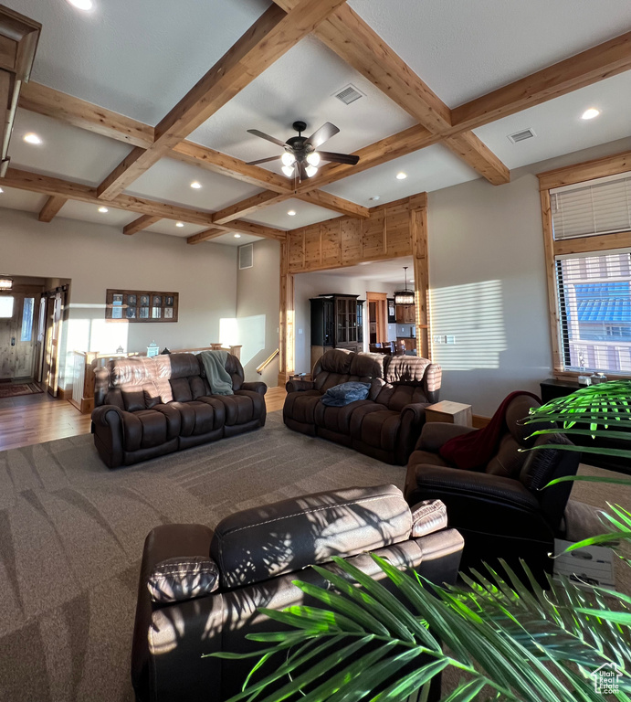 Living room with a wealth of natural light, ceiling fan, and coffered ceiling