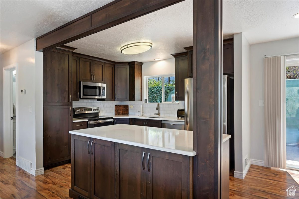 Kitchen with appliances with stainless steel finishes, dark hardwood / wood-style floors, and a healthy amount of sunlight