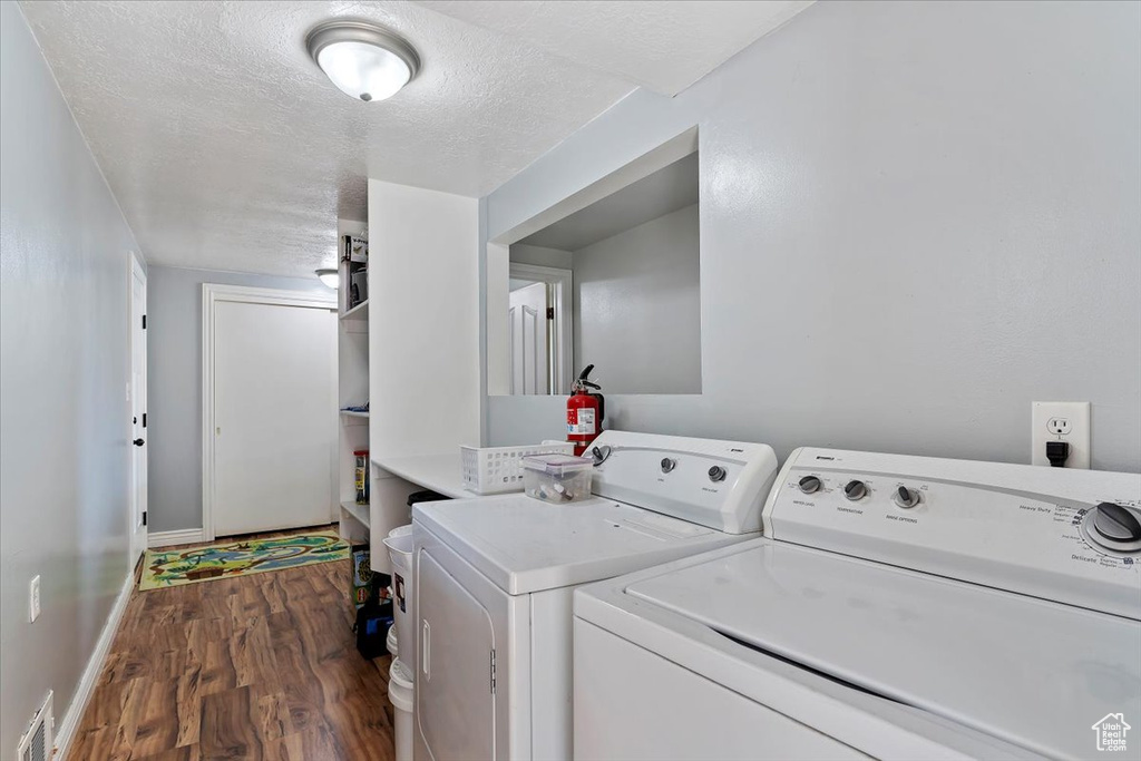 Clothes washing area featuring dark hardwood / wood-style flooring, washer and dryer, and a textured ceiling