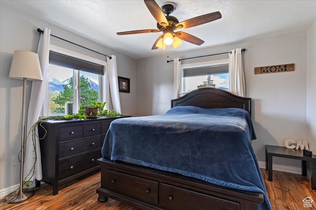 Bedroom with dark hardwood / wood-style flooring, ceiling fan, and a textured ceiling