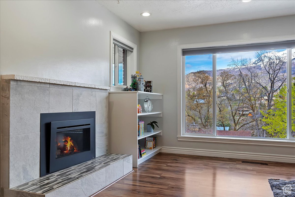 Unfurnished room featuring a tile fireplace, dark hardwood / wood-style floors, and built in shelves