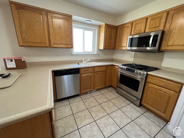 Kitchen featuring sink, light tile floors, and stainless steel appliances