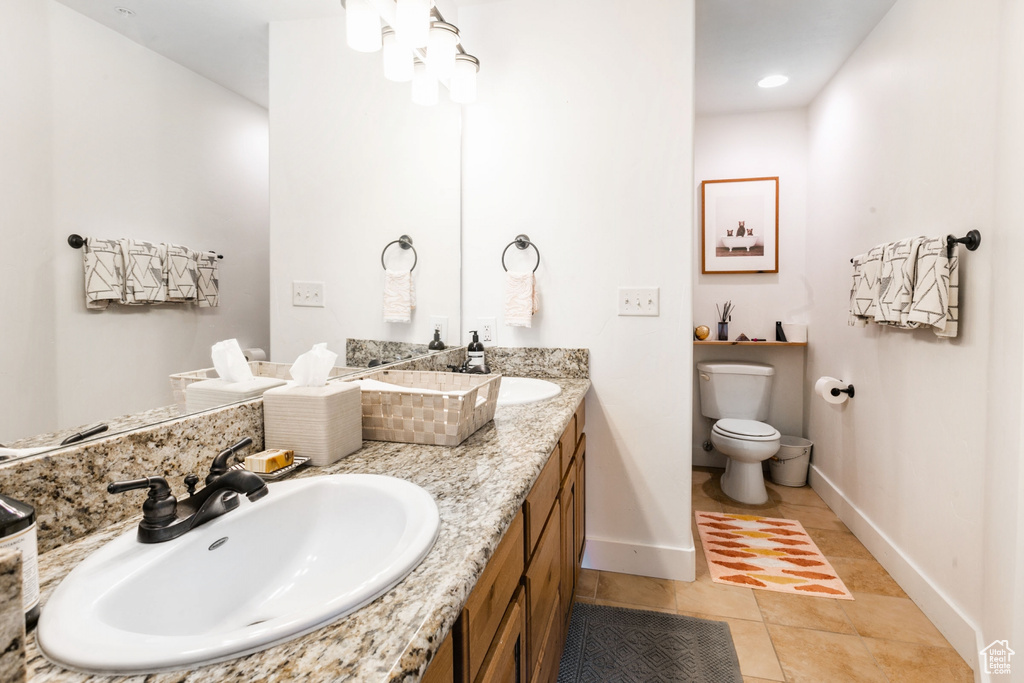 Bathroom featuring large vanity, tile floors, toilet, and double sink