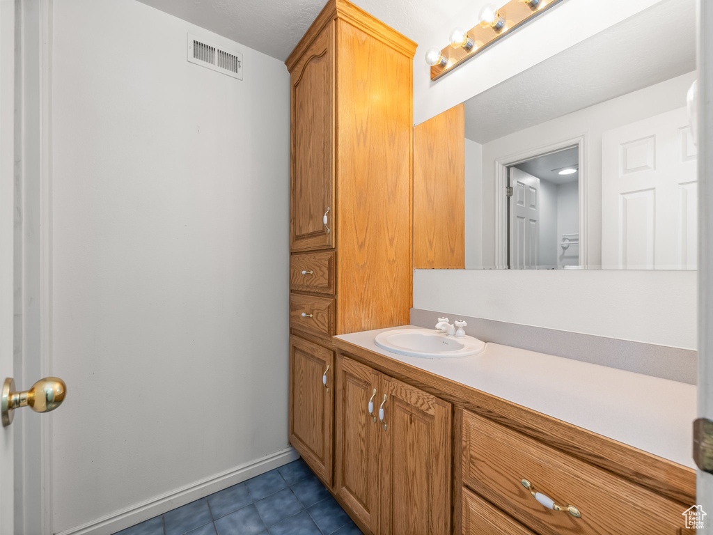 Bathroom with tile flooring and vanity with extensive cabinet space