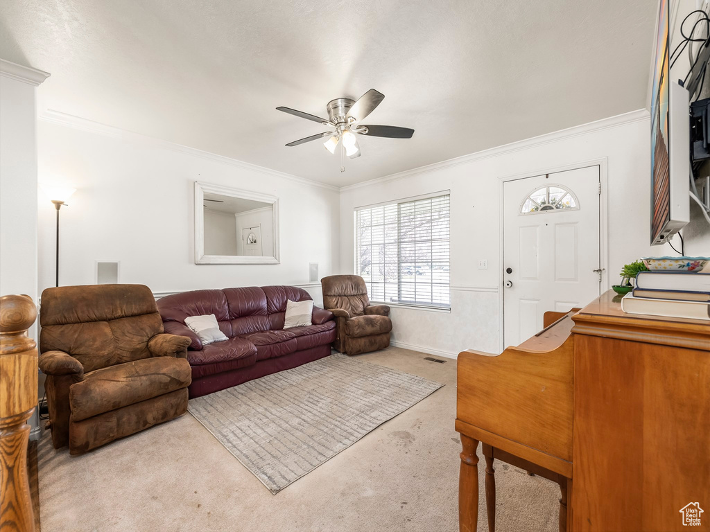 Carpeted living room with ornamental molding and ceiling fan