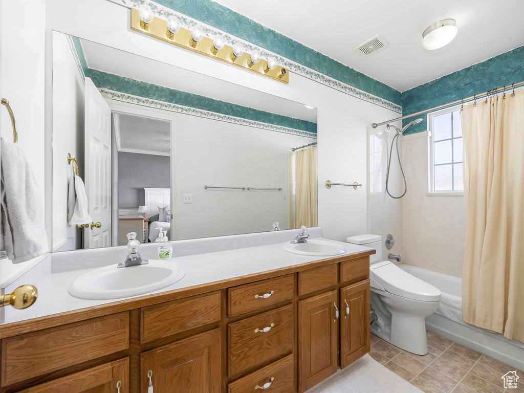 Full bathroom featuring shower / bath combo with shower curtain, tile floors, toilet, and double sink vanity