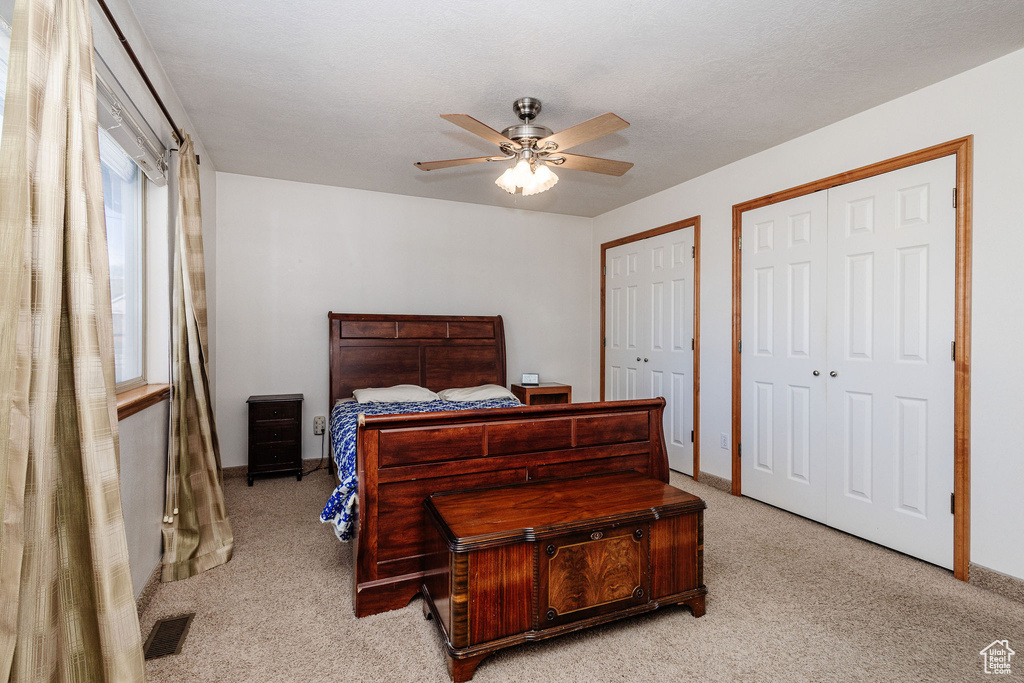 Bedroom featuring two closets, ceiling fan, and light carpet