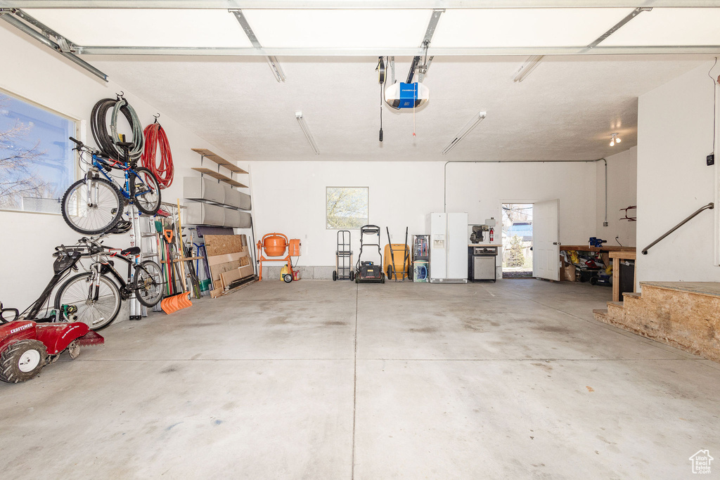 Garage with white fridge with ice dispenser and a garage door opener