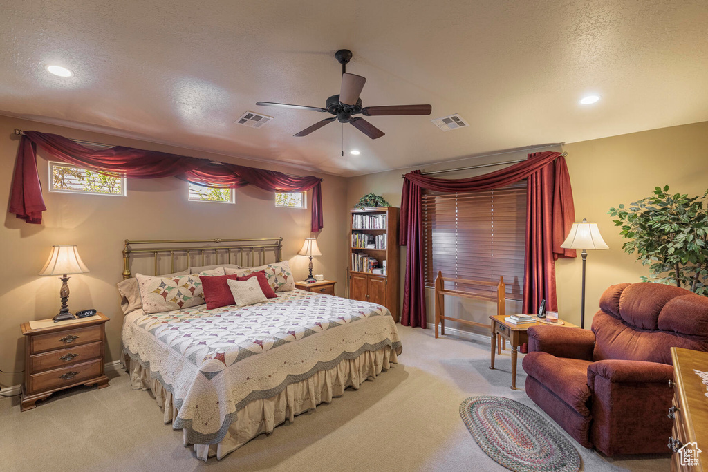 Bedroom featuring a textured ceiling, ceiling fan, and light carpet