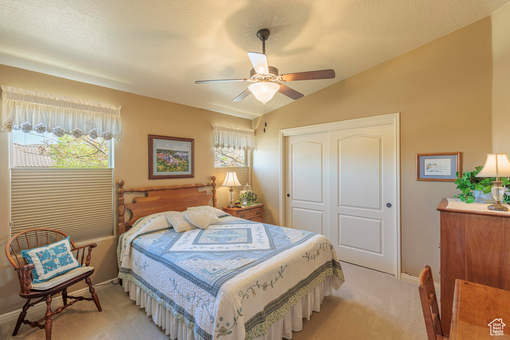 Carpeted bedroom featuring a closet, ceiling fan, vaulted ceiling, and multiple windows