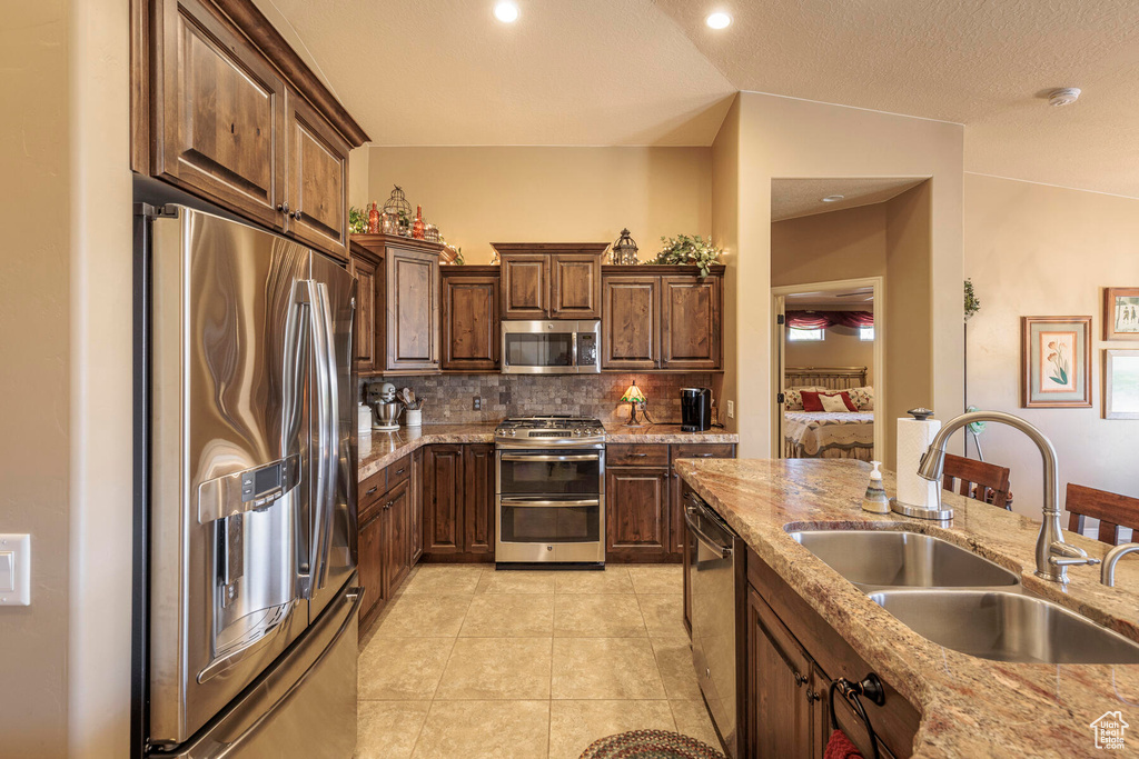 Kitchen featuring appliances with stainless steel finishes, lofted ceiling, tasteful backsplash, and sink