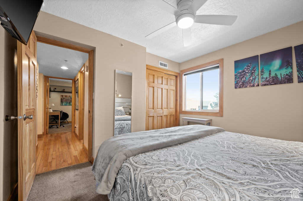 Bedroom with a closet, ceiling fan, carpet, and a textured ceiling