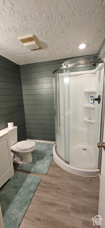 Bathroom featuring walk in shower, a textured ceiling, wood walls, and hardwood / wood-style flooring