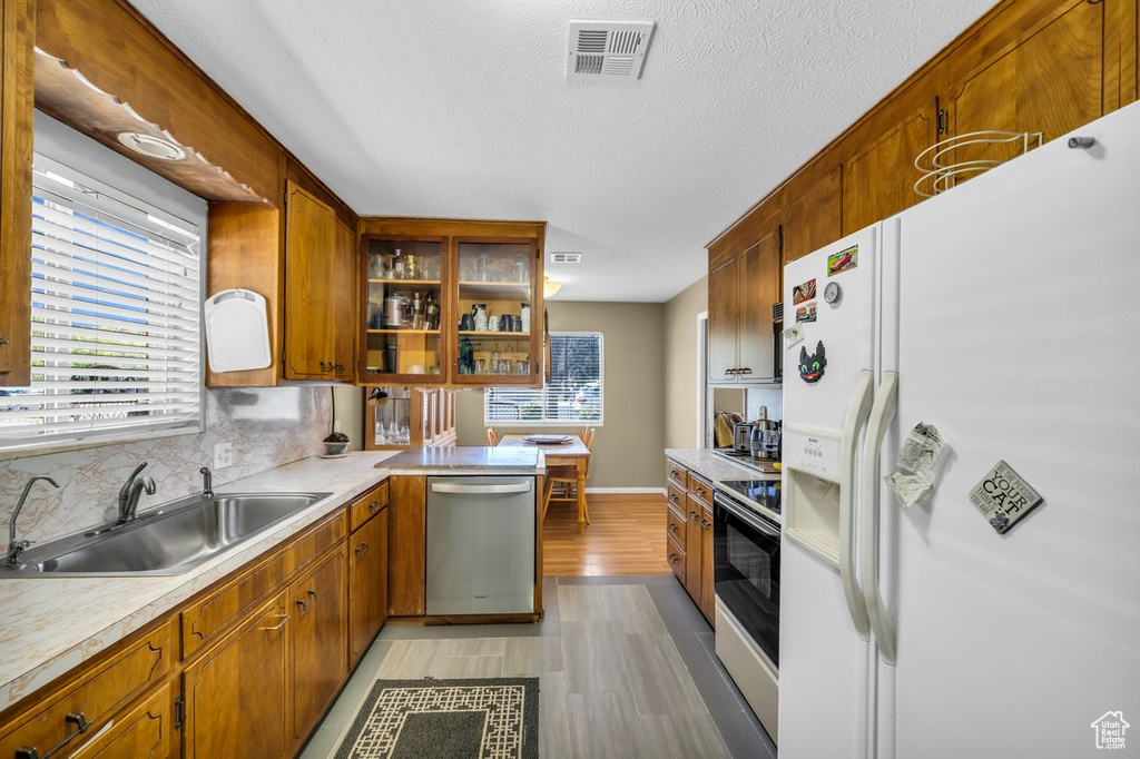 Kitchen with white fridge with ice dispenser, dishwasher, electric stove, and a wealth of natural light