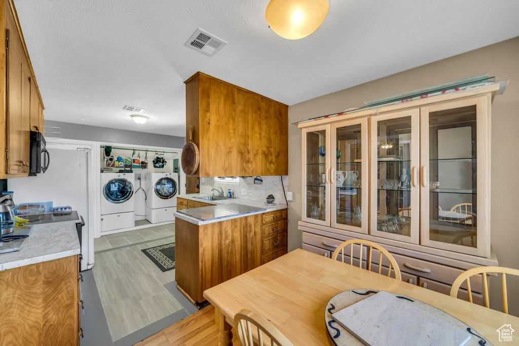 Kitchen with backsplash, washing machine and clothes dryer, light tile floors, sink, and a textured ceiling