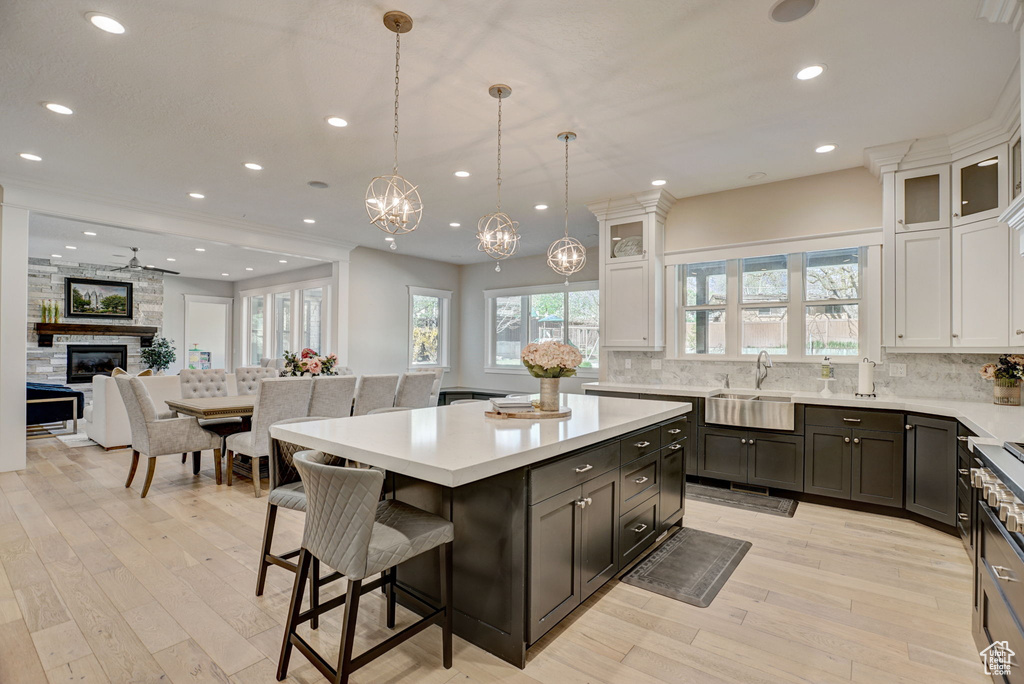 Kitchen featuring pendant lighting, white cabinets, a fireplace, tasteful backsplash, and light hardwood / wood-style floors